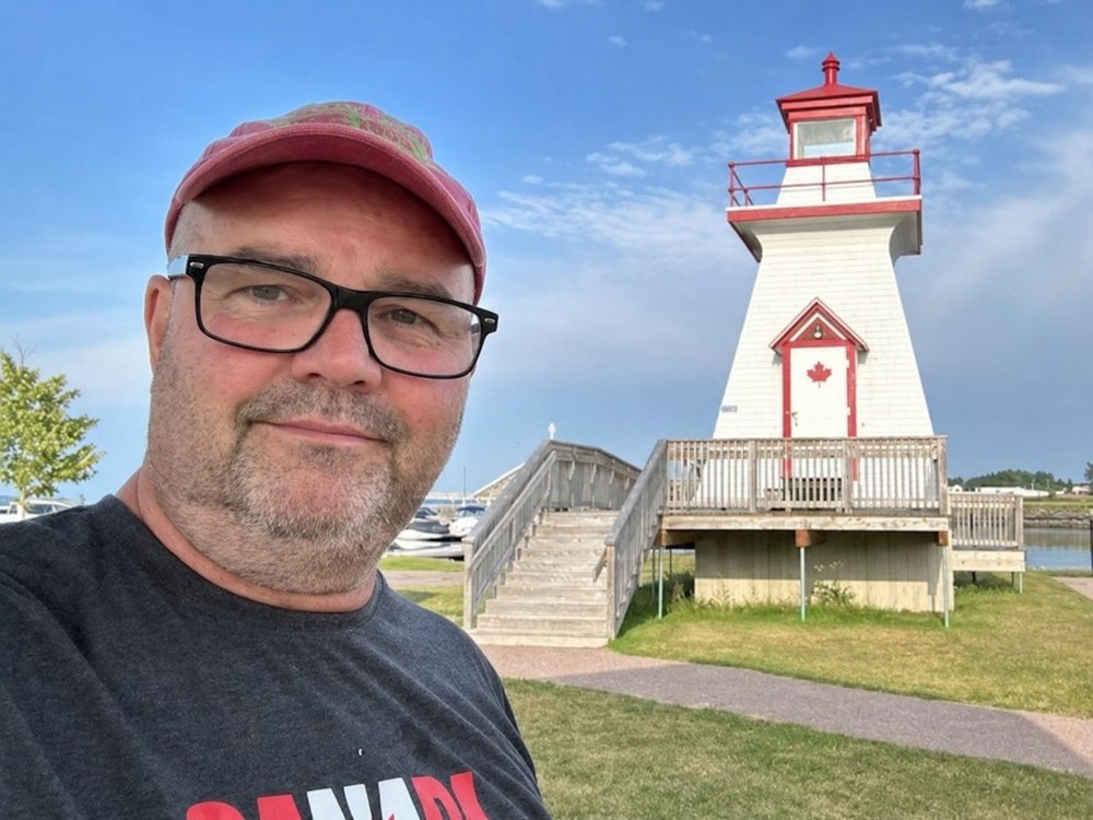 Stuart, VE9CF, creator of ParkWatch, at a red-and-white lighthouse on the Atlantic Canada coast